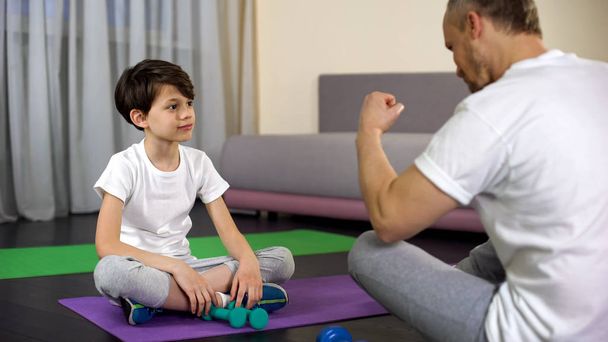 Father praising son during home workout, teaching him doing fitness, sport - Photo, Image