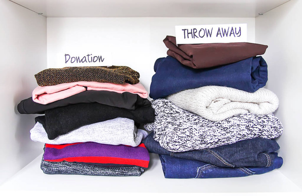 Clothes sorting in home wardrobe on white shelf background. Donation, throw away paper notes. - Photo, Image