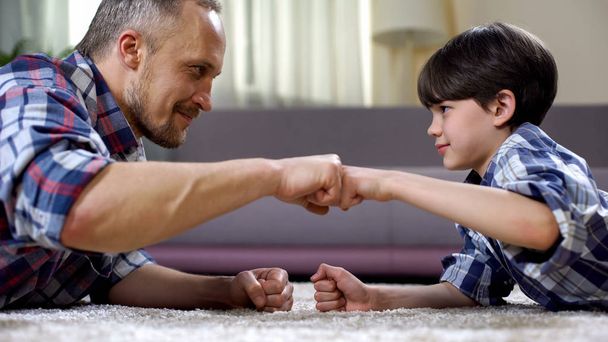 Stepfather and child fist bumping, partnership greeting, happy childhood moment - Foto, afbeelding