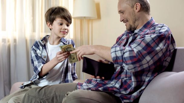 Menino filho pedindo pai para dar mais dinheiro de bolso, necessidades financeiras, paternidade
 - Foto, Imagem