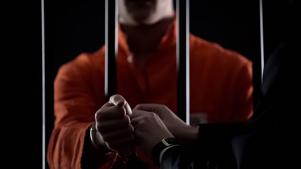 Guard taking handcuffs off criminal, releasing from jail due to good behavior - 写真・画像