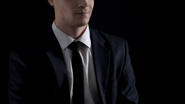 Man in suit smirking, isolated on black background, unfair business concept - Photo, Image