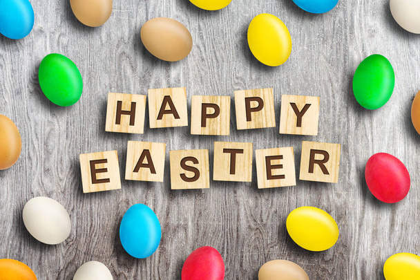 Vícebarevné velikonoční vajíčka na dřevěné pozadí. Veselé Velikonoce, slovo napsané na dřevo bloku. Velikonoce. - Fotografie, Obrázek