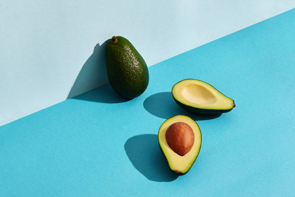 Komposition aus frischen Früchten, ganzer Avocado und zwei Hälften geschnittener Avocado - Foto, Bild