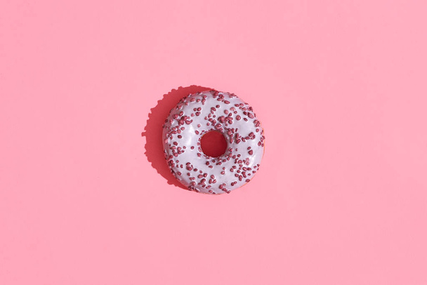 Design alimentaire. Gros plan image de haute qualité de beignet glacé rose sur fond rose corail
 - Photo, image