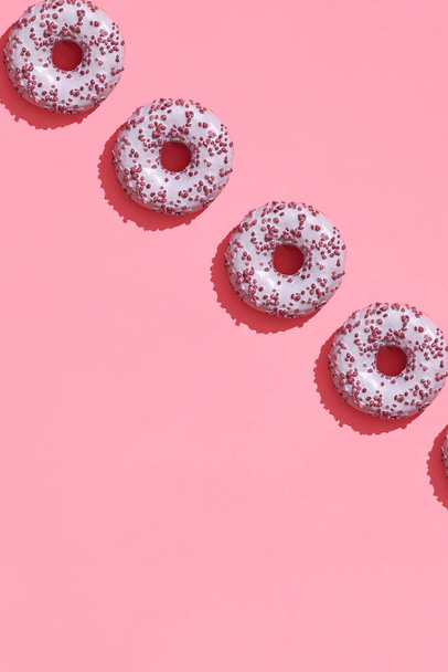 Design de alimentos com saboroso donut de vidro rosa no coral rosa pastel fundo padrão vista superior
 - Foto, Imagem