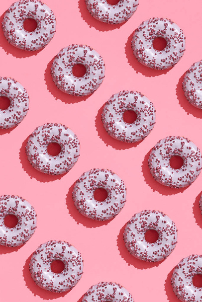 Дизайн їжі зі смачно-рожевим глазурованим пончиком на кораловому рожевому пастельному фоні зверху візерунок
 - Фото, зображення