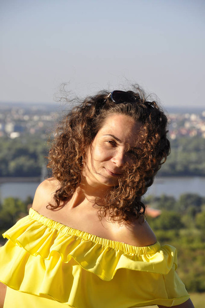 jeune fille heureuse bouclée aux cheveux bruns dans une robe jaune avec s nu
 - Photo, image
