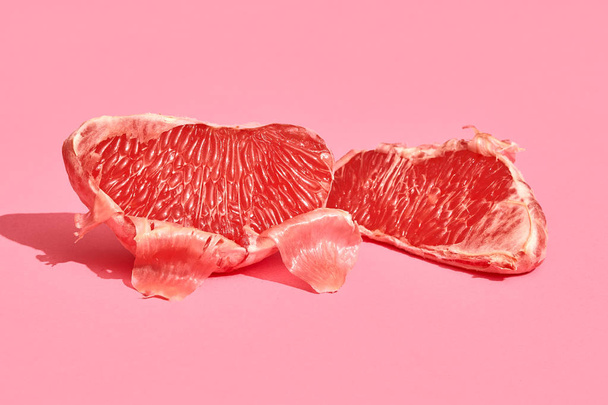 Close up high quality image of peeled slices of juicy grapefruit on a pink background - Foto, afbeelding