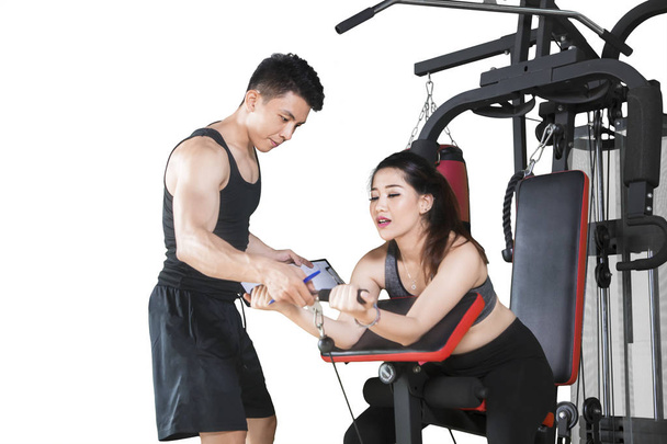 Mujer asiática utiliza máquina de ejercicio con su entrenador
 - Foto, imagen