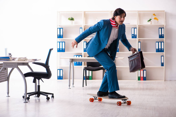 Joven hombre de negocios guapo con longboard en la oficina
  - Foto, imagen