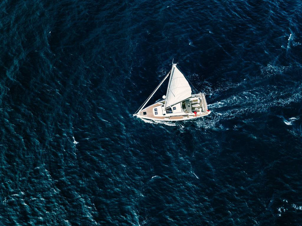 Вид с воздуха на парусные яхты с белыми парусами в глубоком синем море
 - Фото, изображение
