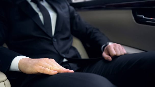Нервовий чоловік у костюмі, сидячи на задньому сидінні автомобіля, запізнився на важливу зустріч
 - Фото, зображення