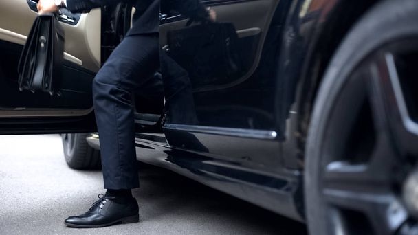Successful businessman getting out of premium class car, arrival to workplace - 写真・画像