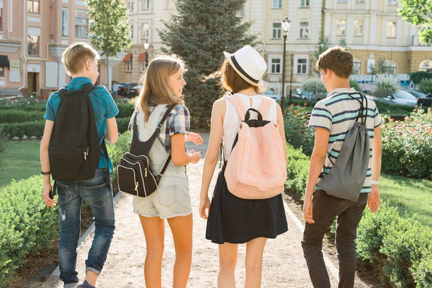 Jovens amigos caminhando na cidade, um grupo de adolescentes falando sorrindo se divertindo na cidade, vista pelas costas. Conceito de amizade e pessoas
 - Foto, Imagem