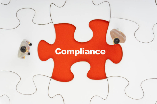 Compliance inschrijving geschreven op Jigsaw Puzzle en zakenman miniatuur. Business en motivatie concept - Foto, afbeelding