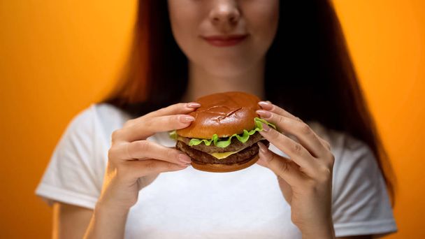 Girl looking at burger, enjoying fast food, high calorie nutrition, obesity risk - Foto, immagini