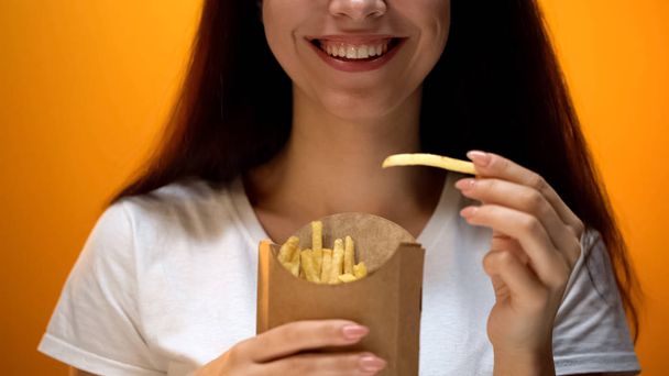 Happy girl holding french fries, artificial flavors and enhanced taste addiction - Fotografie, Obrázek
