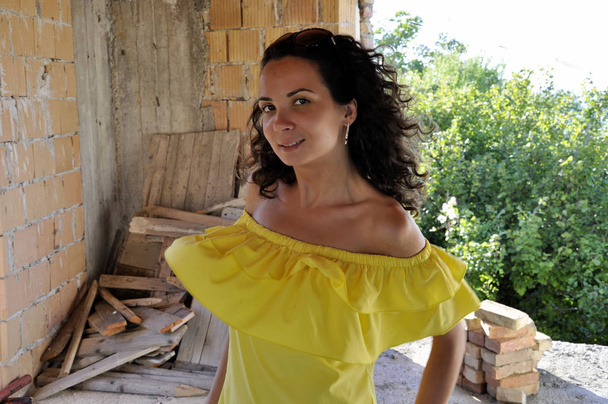 young happy curly dark-haired girl in a yellow dress with bare s - Photo, Image
