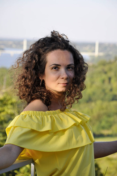 young happy curly dark-haired girl in a yellow dress with bare s - Photo, Image