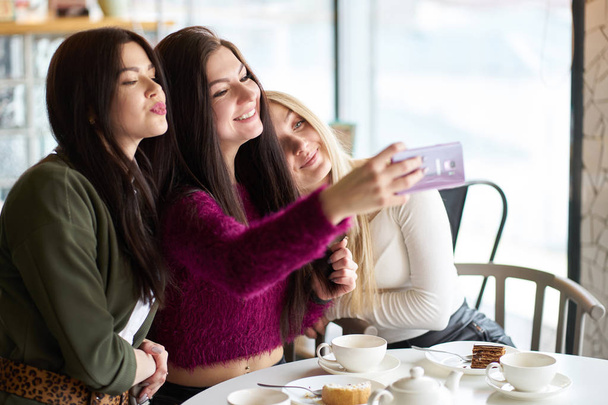 Copines ont du plaisir dans le café, boire du thé et faire du selfie
 - Photo, image