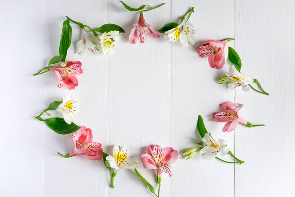 Frame for the text of congratulations with natural flowers of Alstroemeria on a wooden background. Design greeting card with natural colors. Background for text with alstromeria. Flat lay, top view. - Photo, image