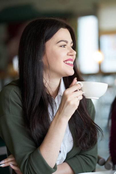 Brunette young white girl drinking tea in cafe and smiling - Foto, immagini
