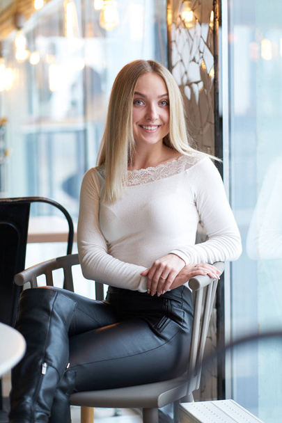 Portrait of young blonde smiling girl sitting near window - Fotoğraf, Görsel