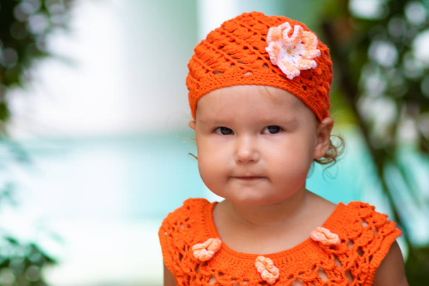 Девушка в апельсиновом трикотажном платье и шляпе удивляется, радуется, кричит, плачет, поднимает руки. детская мода
. - Фото, изображение