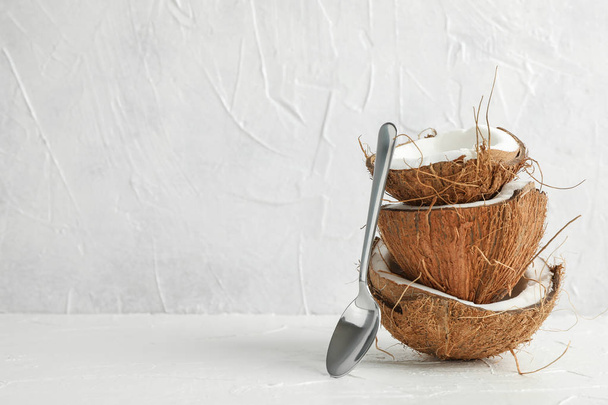 Tropische Kokosnuss mit Löffel auf Holztisch gegen Weiß stapeln  - Foto, Bild