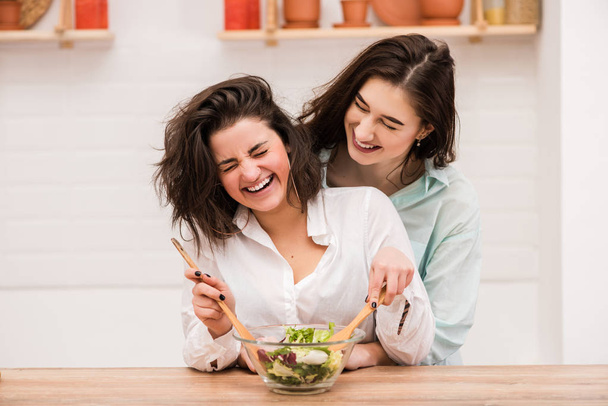 Dos mujeres jóvenes cocinando y abrazándose en la cocina
. - Foto, imagen