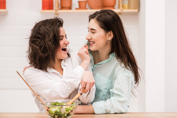 glückliches gleichgeschlechtliches Paar füttert einander in der Küche - Foto, Bild