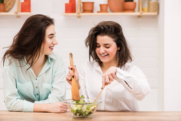 Happy lesbian couple cooking food in kitchen - Фото, зображення