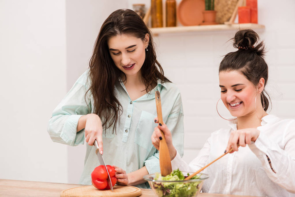 Dwie młode dziewczyny, wspólne gotowanie zdrowe sałatki - Zdjęcie, obraz