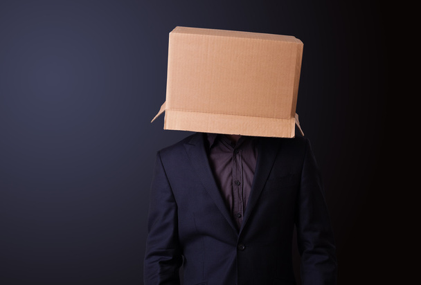 Young man gesturing with a cardboard box on his head - 写真・画像