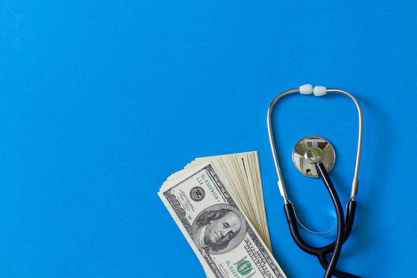 Costly treatment. Stethoscope and dollars on blue background - Foto, imagen