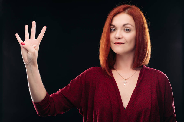 Vonzó vörös hajú lány feltartotta a kezét a 4 ujj. - Fotó, kép