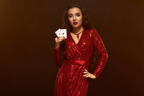 Joven morena hermosa suerte en un vestido de noche rojo muestra sus tarjetas, un par de ases
 - Foto, Imagen