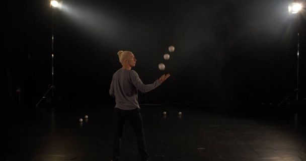 Malabarista en el estudio negro hace trucos con cinco bolas
. - Foto, Imagen