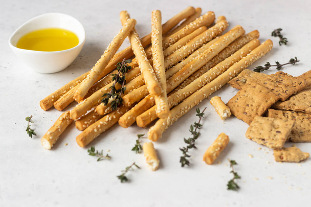 Italian grissini or salted bread sticks and multigrain crackers on a light stone background. Copy space.  - Foto, Imagen