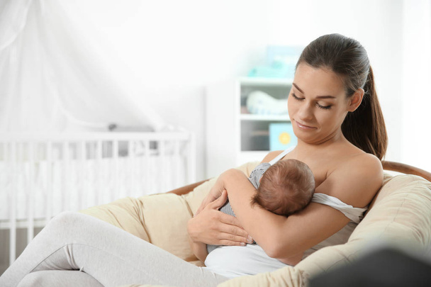 Young woman breastfeeding her baby in nursery. Space for text - Valokuva, kuva