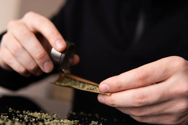 Man rolling a marijuana weed blunt. Man rolling marijuana cannabis blunt. Close up marijuana joint  - Photo, image