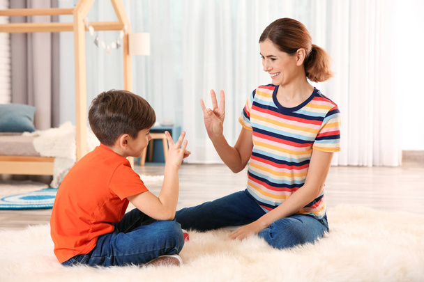 Hearing impaired mother and her child talking with help of sign language indoors - Photo, image