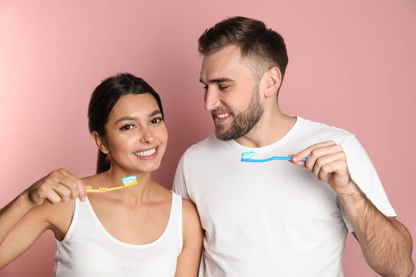 Young couple with toothbrushes and paste on color background. Teeth care - Foto, Imagem