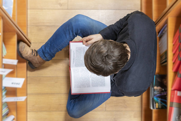 Κορυφαία θέα του μαθητή να θέσει σε ξύλινο πάτωμα και να διαβάσετε ένα βιβλίο β - Φωτογραφία, εικόνα
