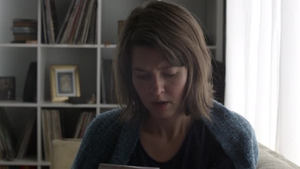 Close view of woman flipping through her mail as she looks off into the distance with a stressed out look on her face. - Materiał filmowy, wideo