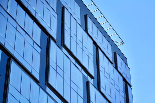 New office building in business center. Wall made of steel and glass with blue sky.  - Photo, Image