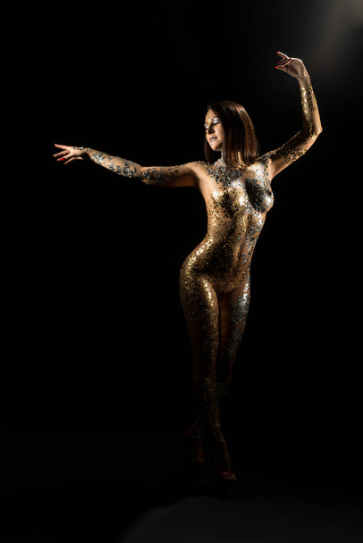 Nude brunette with gold bodyart shot in the dark - Photo, image