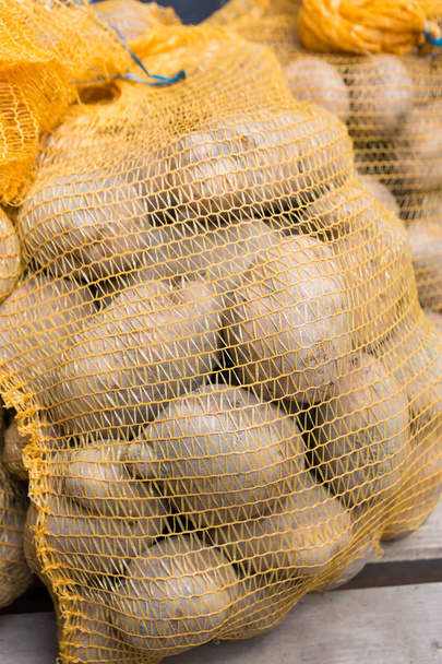 bolsas de papas rústicas crudas alimentos en sacos sobre fondo de madera
 - Foto, imagen