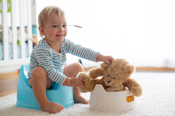 Cute toddler boy, potty training, playing with his teddy bear  - Foto, afbeelding